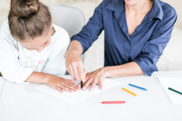 Wall Mural - Happy family. Mother and daughter together paint and draw. Adult woman helps the child girl