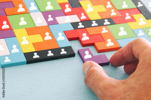 Fotomural image of tangram puzzle blocks with people icons over wooden table ,human resources and management concept