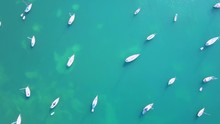 Aerial Drone Shot Of Turquoise Water With Many Sailboats Floating Peacefully In The Caribbean.