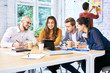 © baranq - Group of students looking at tablet while studying together in university. Young creative workers brainstorming during meeting