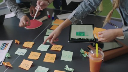 slow motion young multi ethnic team of web developers brainstorming ideas for startup business website planning design layout in modern workspace close up