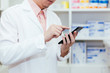 © twinsterphoto - Pharmacist, Physician using a mobile phone at drugstore room. Doctor touching a cell phone in medical concept.