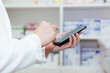© twinsterphoto - Pharmacist, Physician using a mobile phone at drugstore room. Doctor touching a cell phone in medical concept.