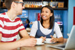 © pressmaster - Happy young woman in casualwear and her colleague sitting by table in cafe, having coffee and discussing news