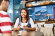 Smiling young businesswoman in casualwear having coffee in cafe with her colleague