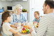 © pressmaster - Happy family of young parents and two little daughters sitting by served table and having breakfast