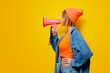 © Masson - Young style girl in jeans clothes with pink megaphone on yellow background. Symbolizes female resistance. Clothes in 1980s style