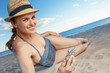 © Alliance - smiling modern woman in swimwear with smartphone on beach