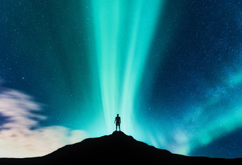 Wall Mural - aurora borealis and silhouette of standing man on the mountain. aurora and traveller. starry sky and