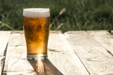 Szklanka piwa na drewnianym blacie.