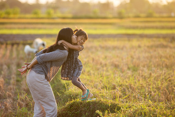 mom and kid hugging under the sunset sky