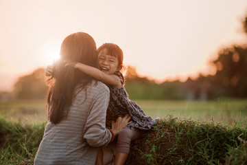 Wall Mural - mom and kid hugging under the sunset sky