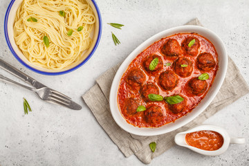 Canvas Print - Pasta and meatballs in tomato sauce with basil in a white dish, top view.