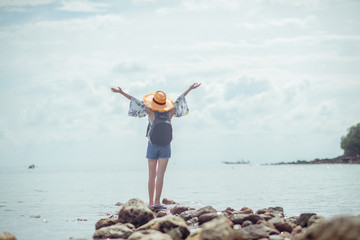 woman standing on the sea beach cheerfully enjoy the nature of the sea, in day of sunny, both hands up on the air