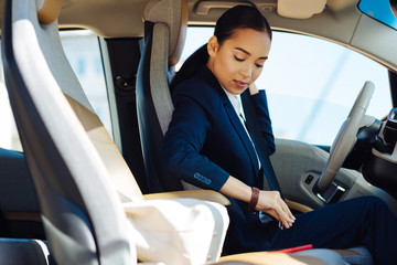 Wall Mural - Being safe. Nice pleasant woman fastening a seatbelt while sitting behind the wheel