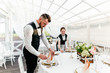 © pantovich - Two male and female waiters serve a table in the restaurant wiping glasses for wine