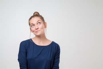 Smiling young woman looking up at gray copy space.