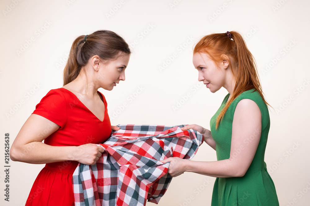 Two beautiful young women fighting for piece of clothing Stock Photo | Adobe Stock Two beautiful young women fighting for piece of clothing Stock Photo | Adobe Stock