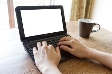 hand using laptop computer with blank white screen on desk