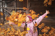 girl throws maple leaves. autumn fun. school holiday. child playing in leaf fall.