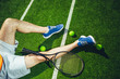 Top view close up male athlete legs wearing sneakers resting on green court. Modern sport equipment for tennis situating near them