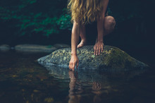 Young Woman Sitting On Rock In A River