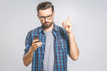 Wall Mural - Idea! Young stylish hipster guy dressed in shirt, holds smart phone, reads something attentively, raises index finger, quotes someone words, proves his rightness. People and technology concept.