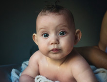 Cute Newborn Baby Just Out Of The Bath With Wet Hair And Face Looking At The Camera