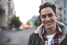 Waist Up Portrait Of Delighted Young Male Standing On Street And Smiling.  He Is Happy To Walk On His Own. Copy Space In Left Side