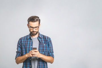 Wall Mural - Happy young man in glasses typing sms on gray background