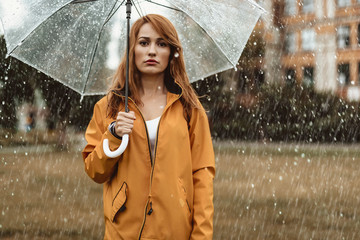 Wall Mural - Waist up portrait of unhappy girl holding umbrella in hands. She is looking at camera with discontent 