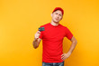 © ViDi Studio - Delivery man in red uniform isolated on yellow orange background. Professional businesslike male employee in cap, t-shirt courier or dealer hold in hand credit bank card. Service concept. Copy space.