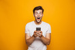 © Drobot Dean - Portrait of a shocked young man holding mobile phone