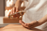 Close up of a woman masseur pouring massage oil
