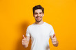© Drobot Dean - Portrait of cheerful man in basic clothing smiling and showing thumbs up at camera, isolated over yellow background
