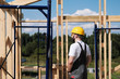 © spaskov - The man is a builder on the roof of a wooden frame house.