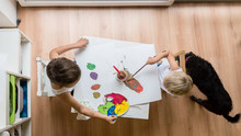 Overhead View Of Two Toddler Children Painting With Water Colours