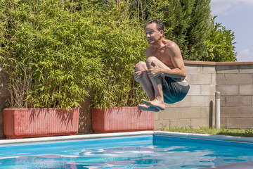 Caucasian man takes a bomb dive in the pool