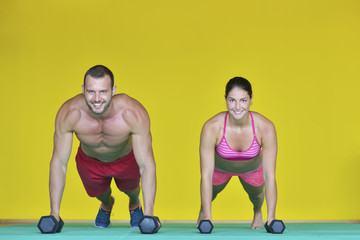 Wall Mural - Beautiful fitness young sporty couple doing push ups together indoors.