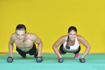 Wall Mural - Beautiful fitness young sporty couple doing push ups together indoors.