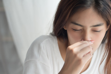 Wall Mural - sick girl sniffle with runny nose; sick woman suffering from cold, flu, runny nose, trying to clear her nose; woman personal health care, pain, sickness concept; asian young adult woman model