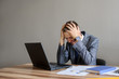 © Med Photo Studio - A business man at a office desk  looking at the project on computer,hands on the head