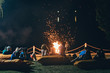© Damian - Group of people near camp fire with campfire song and campfire meals playing campfire games and eating campfire grill, telling campfire stories near the fire with wood, flames in the nature at night.