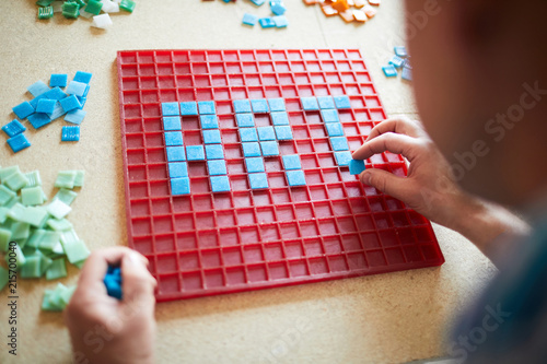 Fotografía Over the shoulder view of unrecognizable craftsman laying out word ART in blue