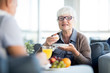 © pressmaster - Portrait of modern senior woman enjoying dessert cake while chatting with husband in cafe