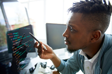 serious concentrated young african-american programmer looking confused while learning coding langua