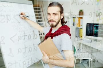 Wall Mural - cheerful positive handsome young caucasian male coding specialist examining code and correcting it o