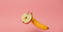 Yellow Banana And Apple Levitate In Air On Pink Background.