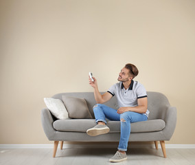 Wall Mural - Young man with air conditioner remote at home