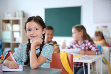 Poster - Cute little child sitting at desk in classroom. Elementary school